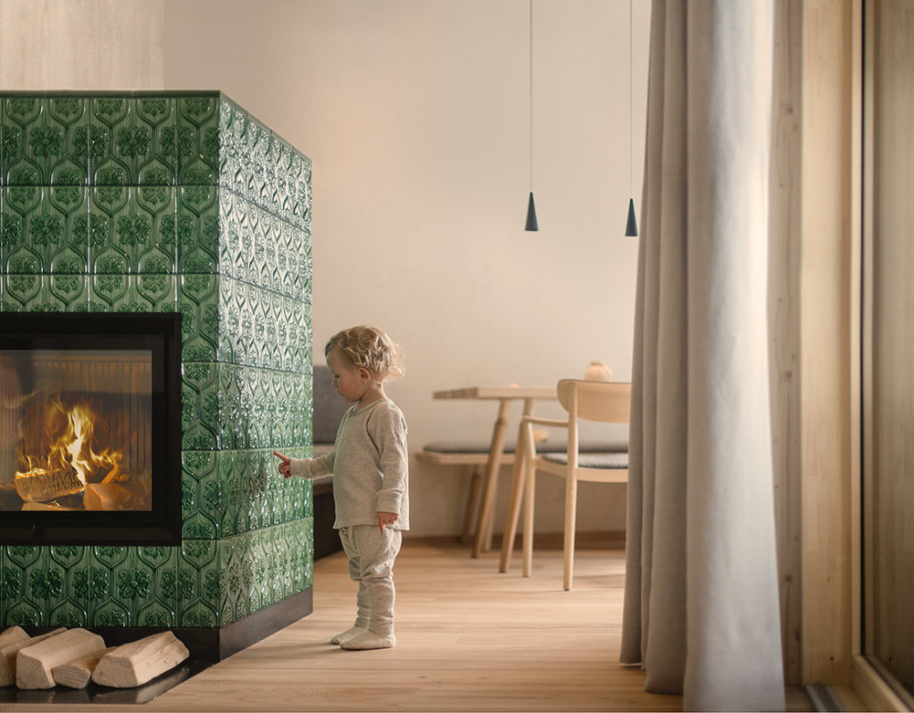 Grüne abgerundete Kacheln sorgen bei dem Kachelofen für ein auffallendes Design.